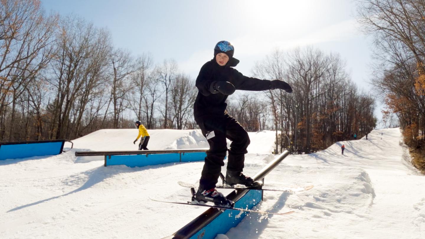 teenage skier going down rail in terrain park