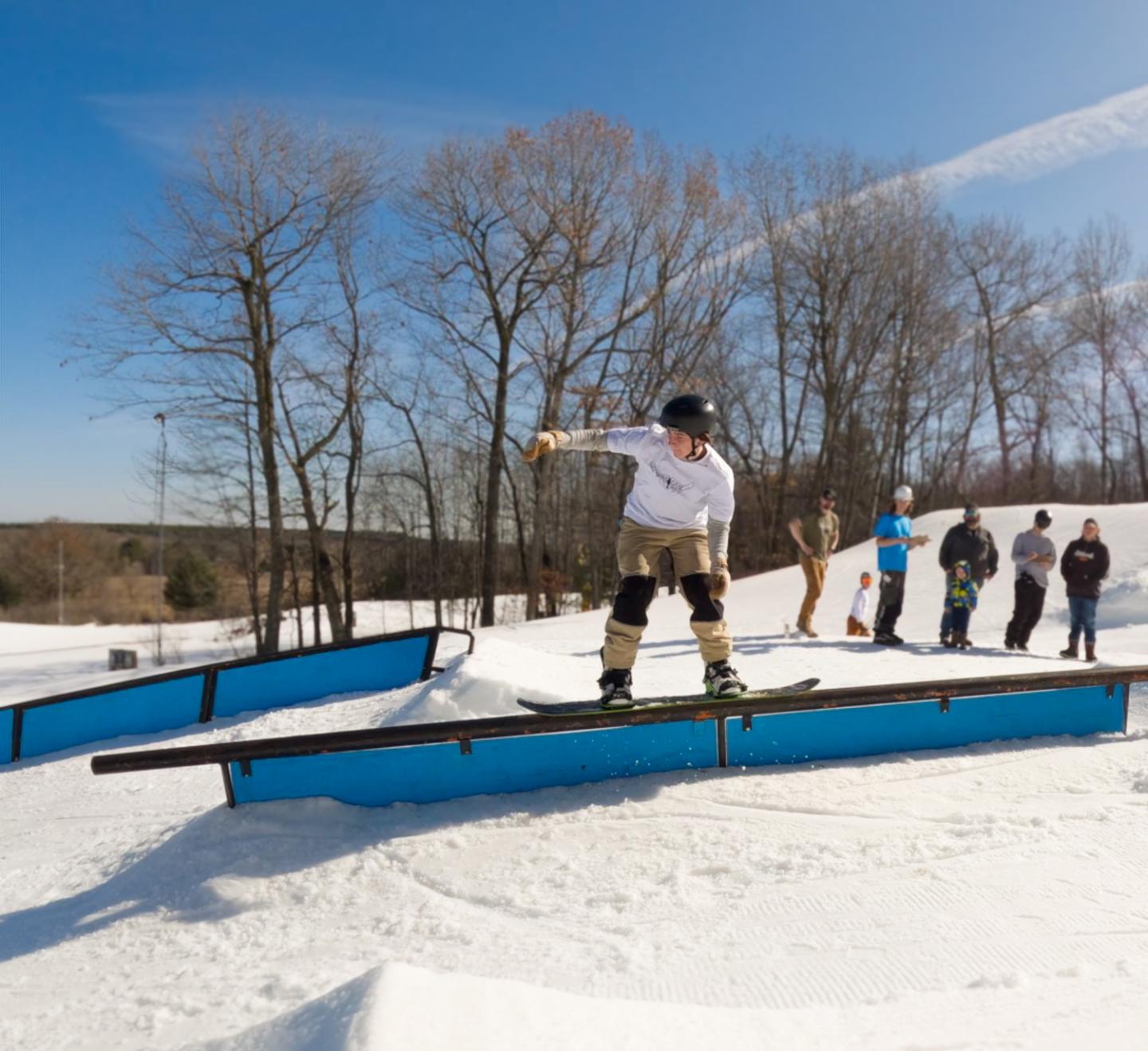 snowboarder riding rail in terrain park
