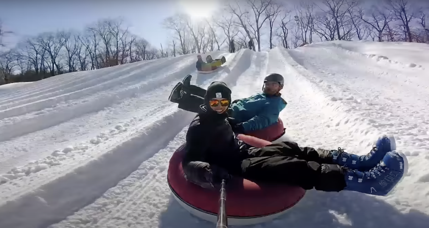 person smiling while going down snow tube track