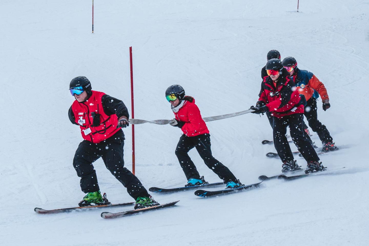 Ski patroller with group tailing behind on mountain