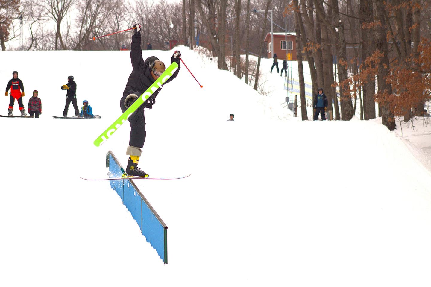 Skier performing a trick on a rail in a snowy landscape.