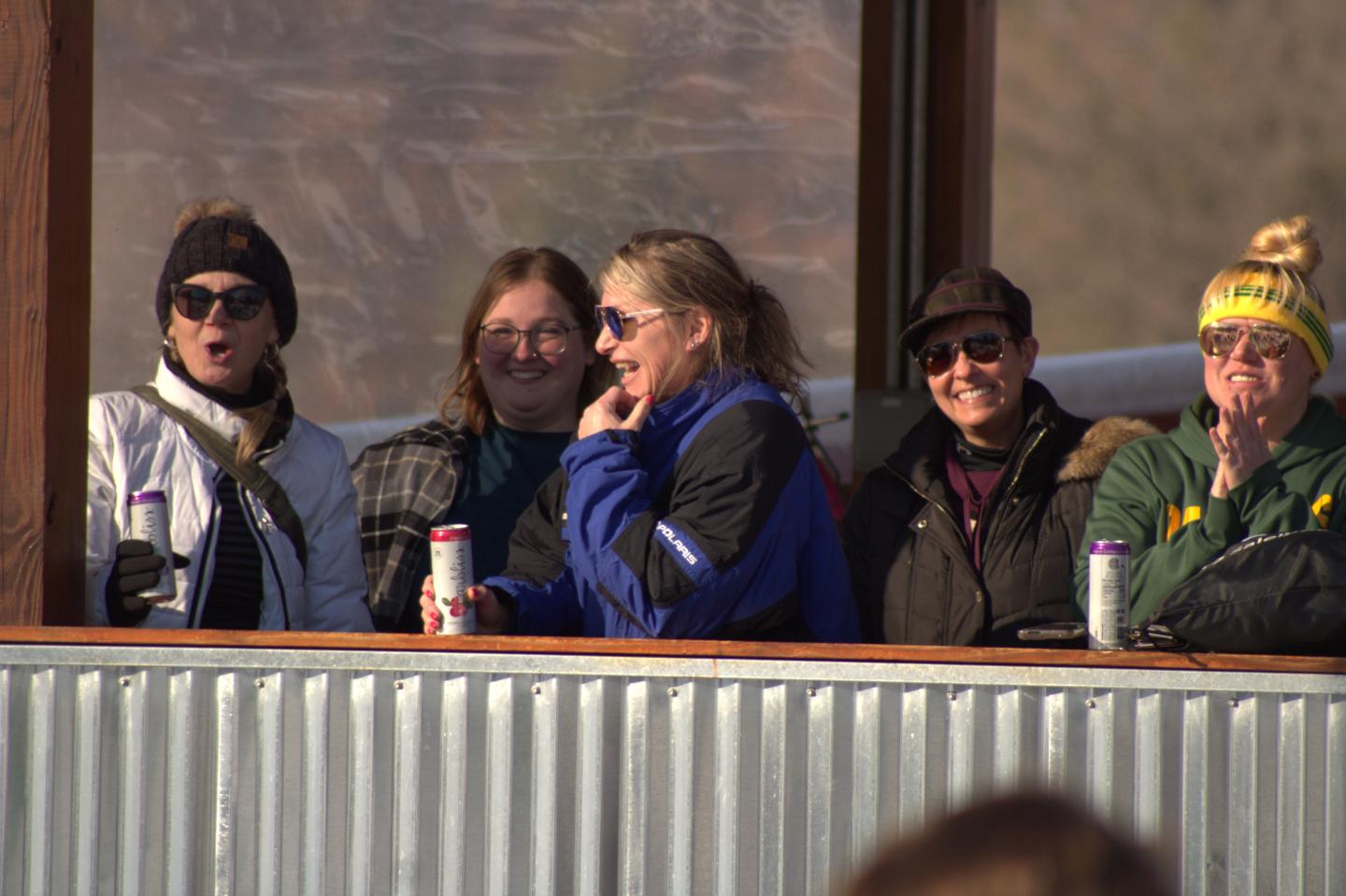 Group of women in winter clothing smiling on a balcony.