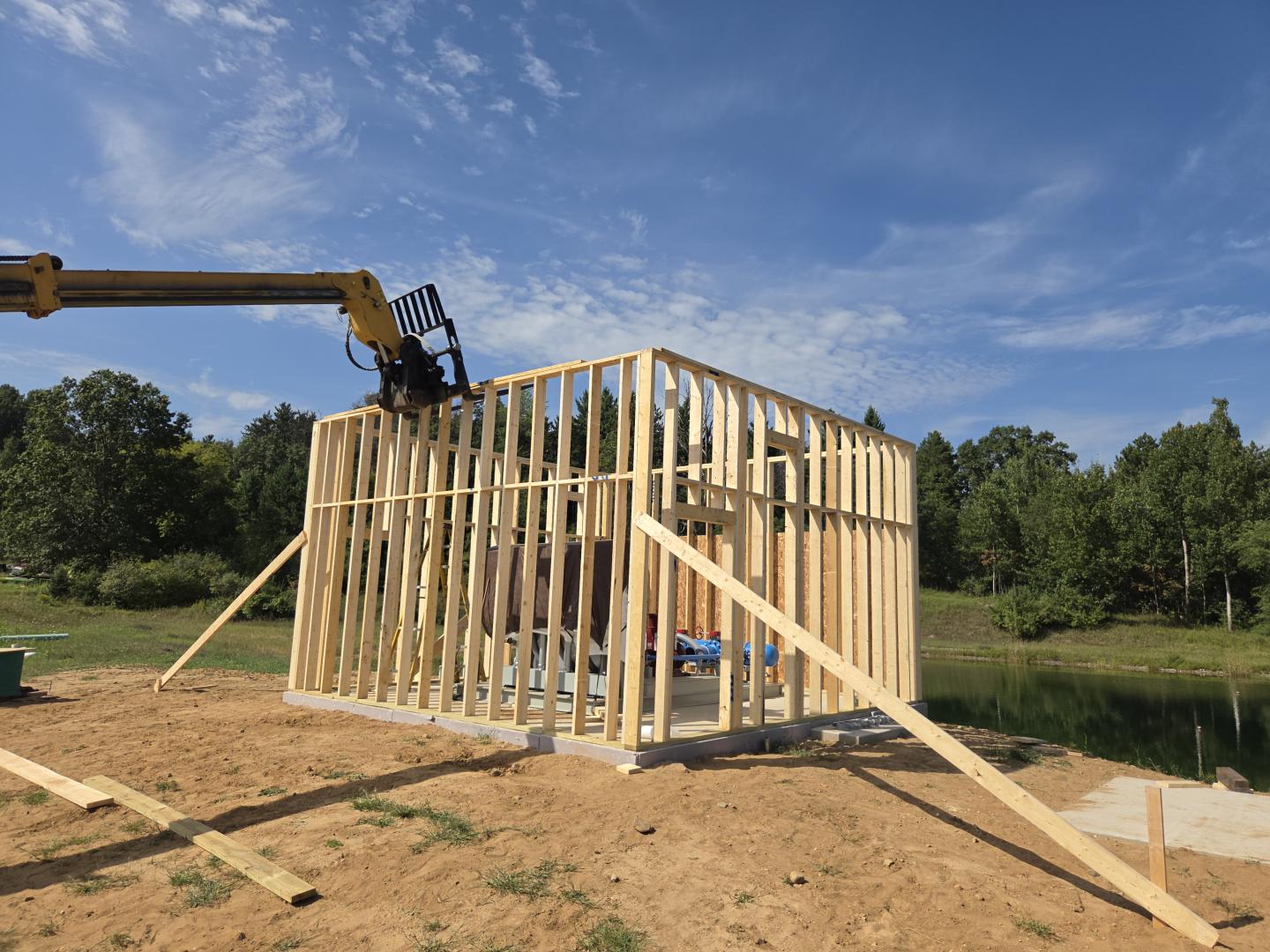 Wood-framed house under construction with a crane lifting lumber.