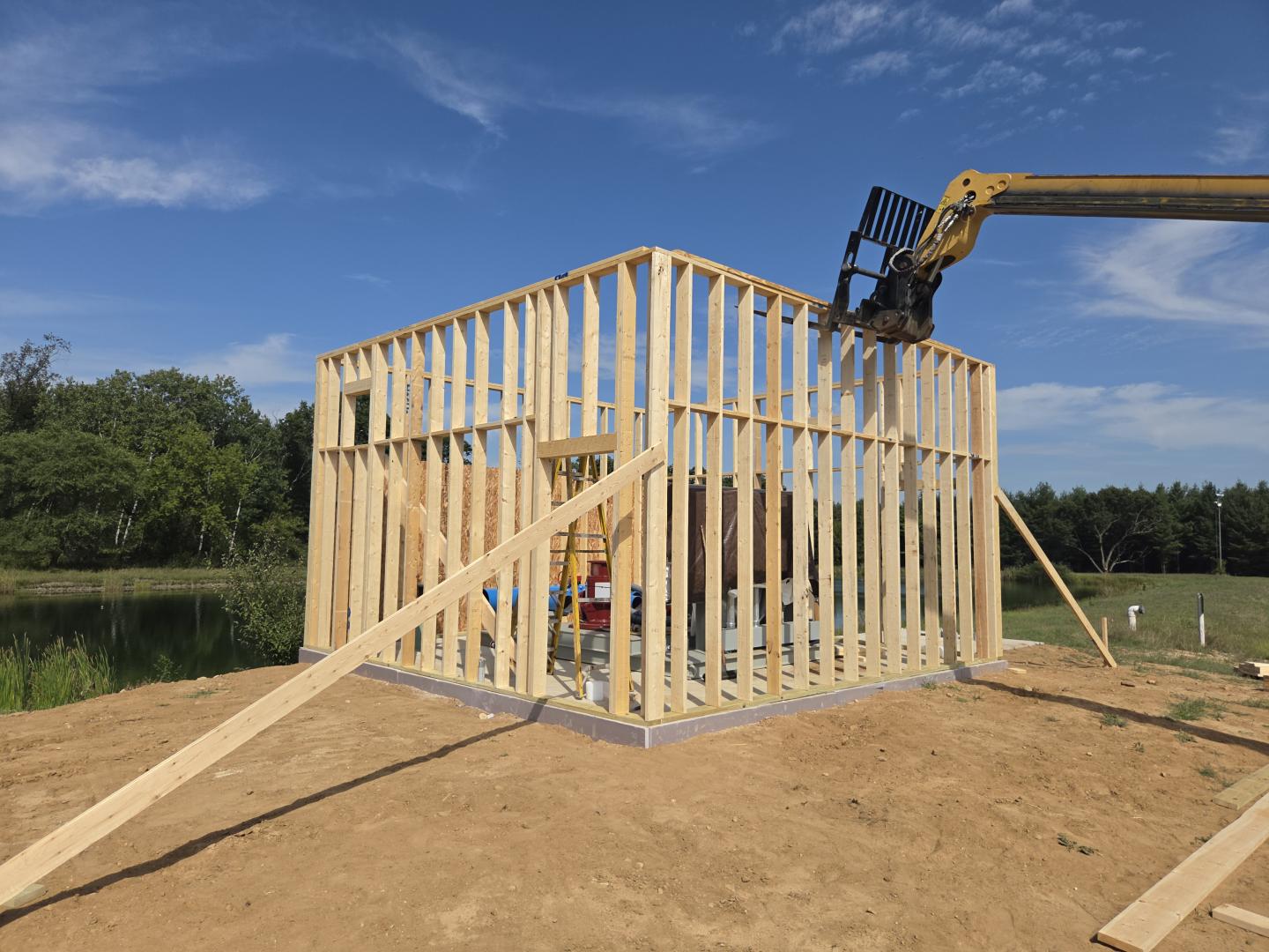 Wooden frame of a house under construction beneath a blue sky.