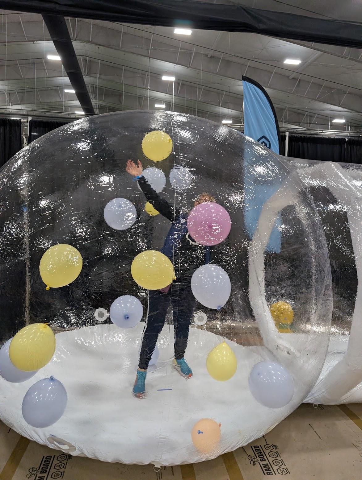 Large transparent inflatable bubble decorated with colorful planet-like spheres indoors