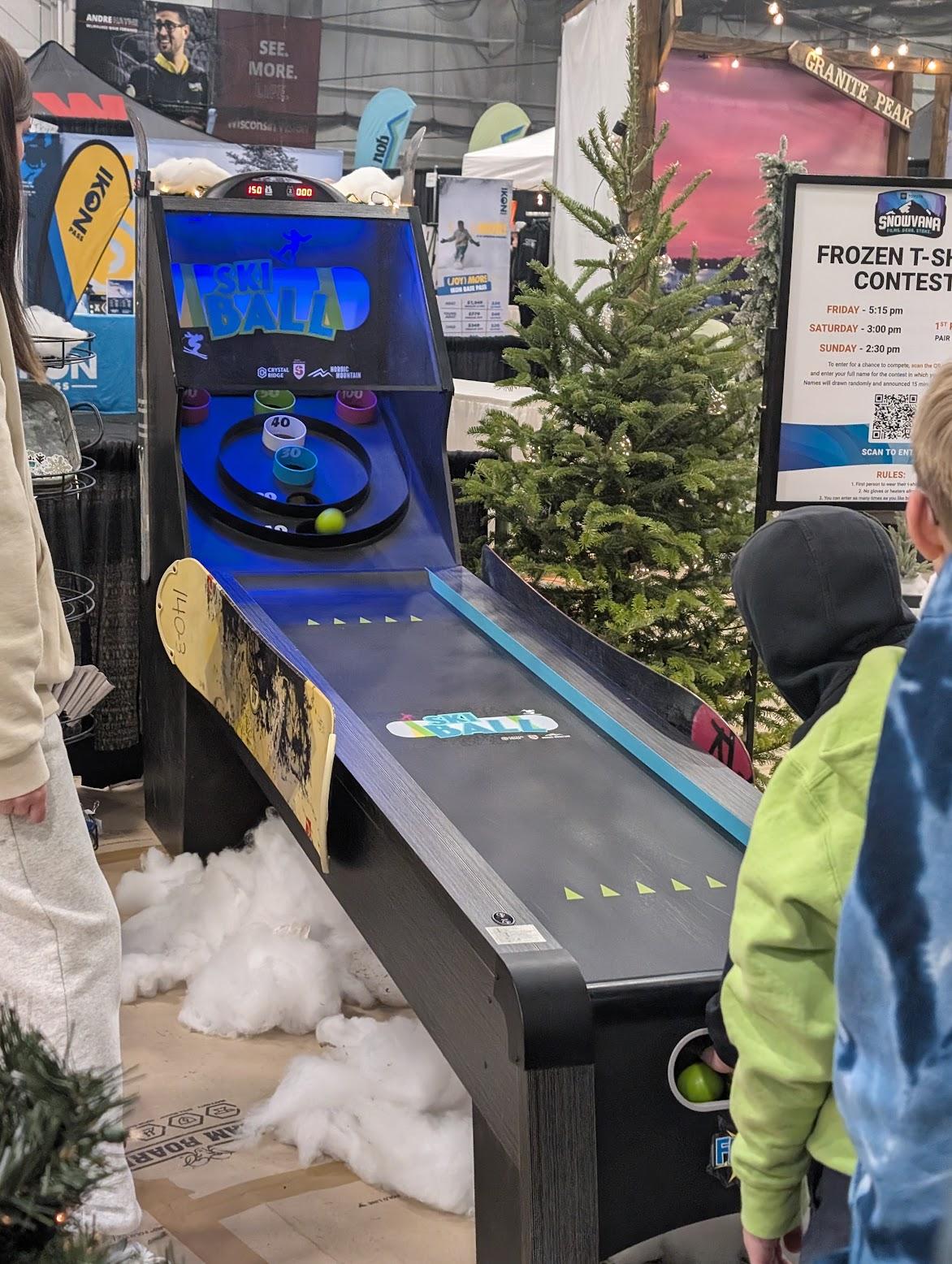 Arcade ski-ball game beside Christmas trees in a store.