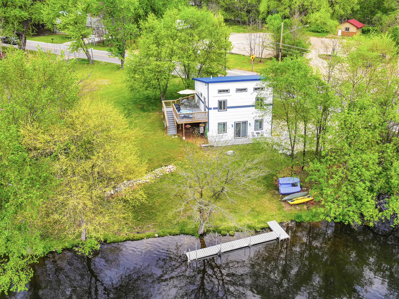 Aerial view of a white lakeside house surrounded by green trees.