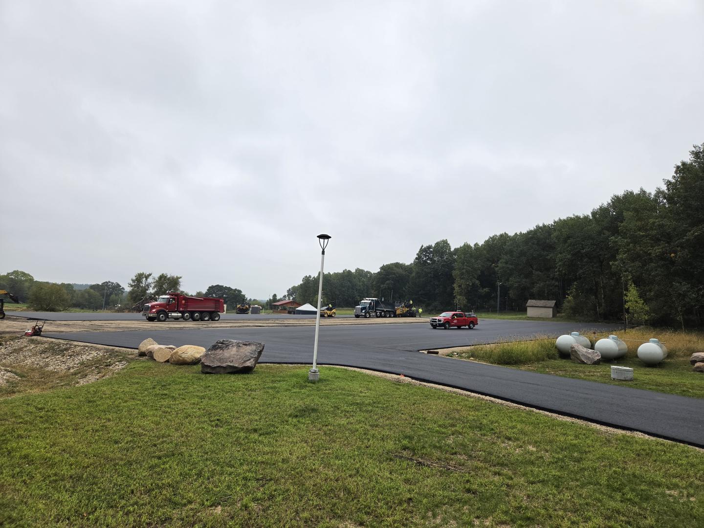 Wide asphalt road curving through a grassy area under an overcast sky.