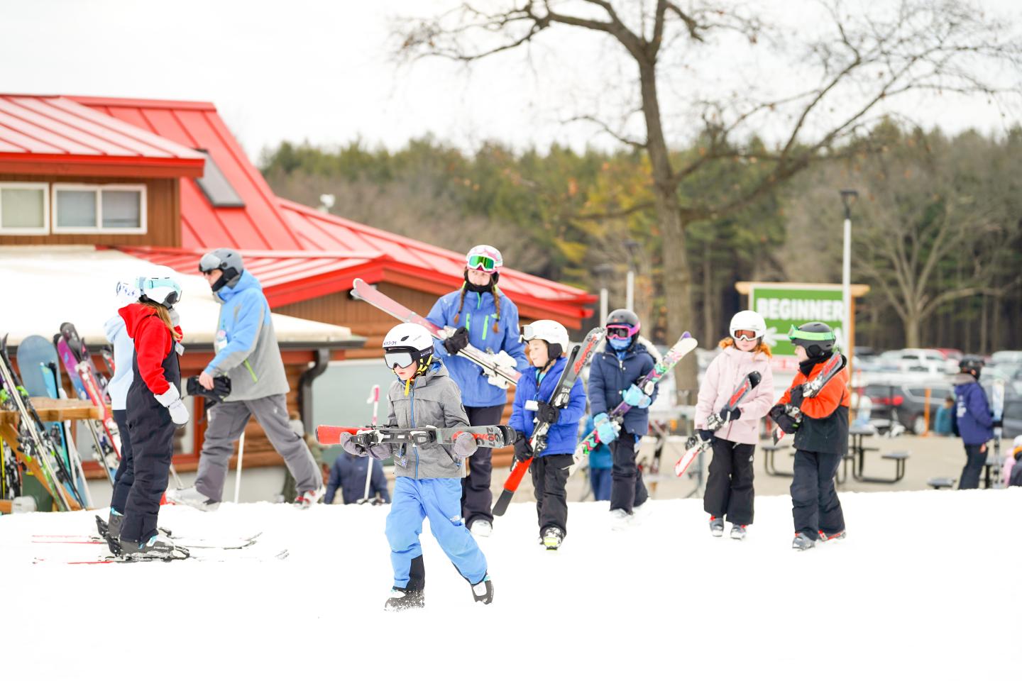Children and adults in martial arts uniforms practice kicks outdoors.